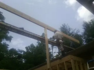 Carpenter setting a ridge beam over a new addition frame — Ice Dam Removal by Roofing Brothers in Penn Run