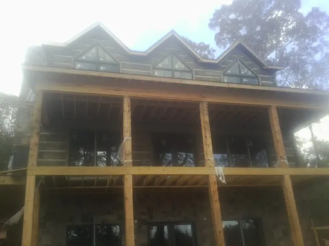 Dormers and porch framing on a large log home under construction — Roof Coating work by our crew in Penn Run