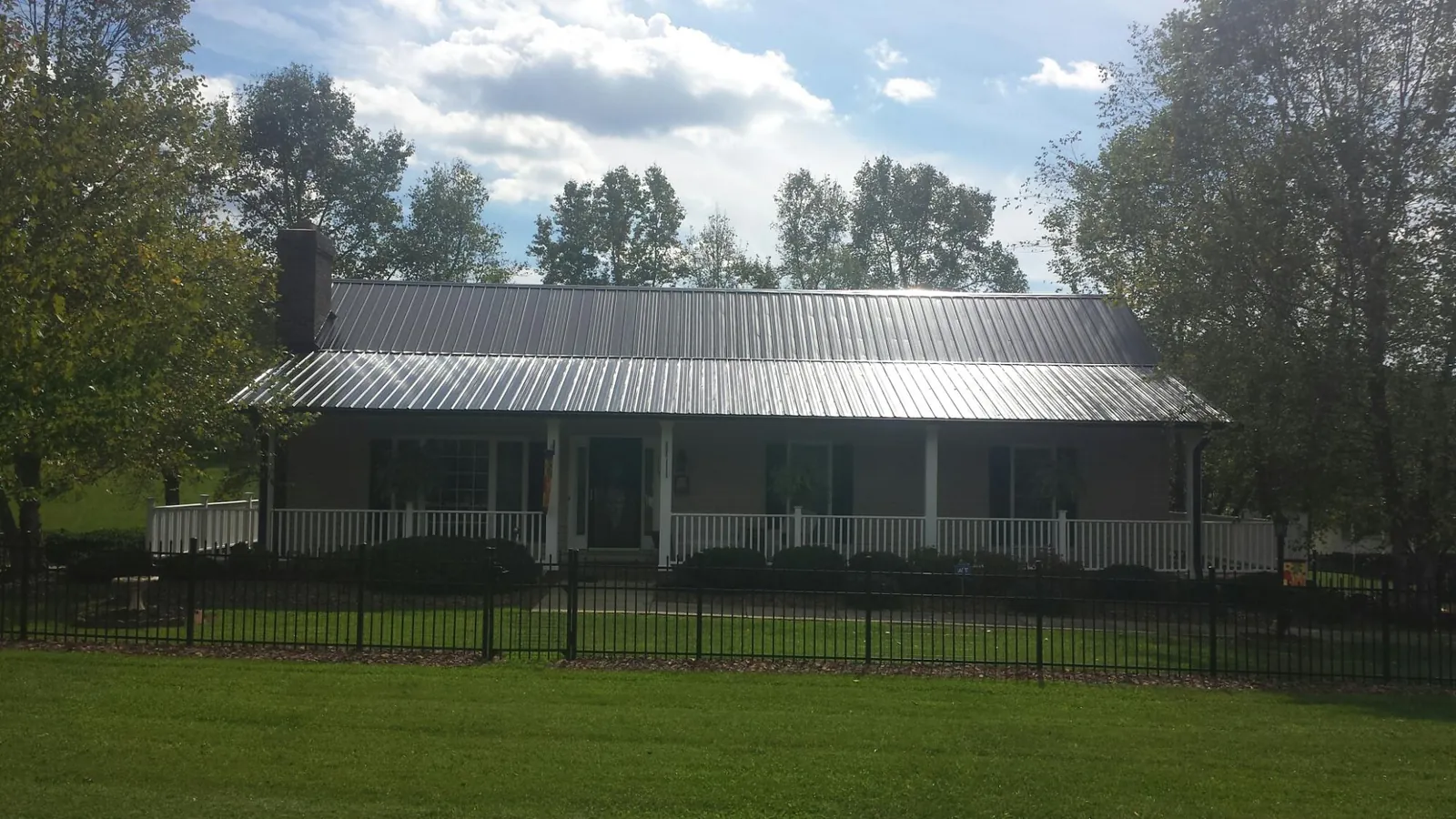Gray metal roof on a brick ranch with a full width front porch — Gutter Guard Installation work by our crew in Penn Run