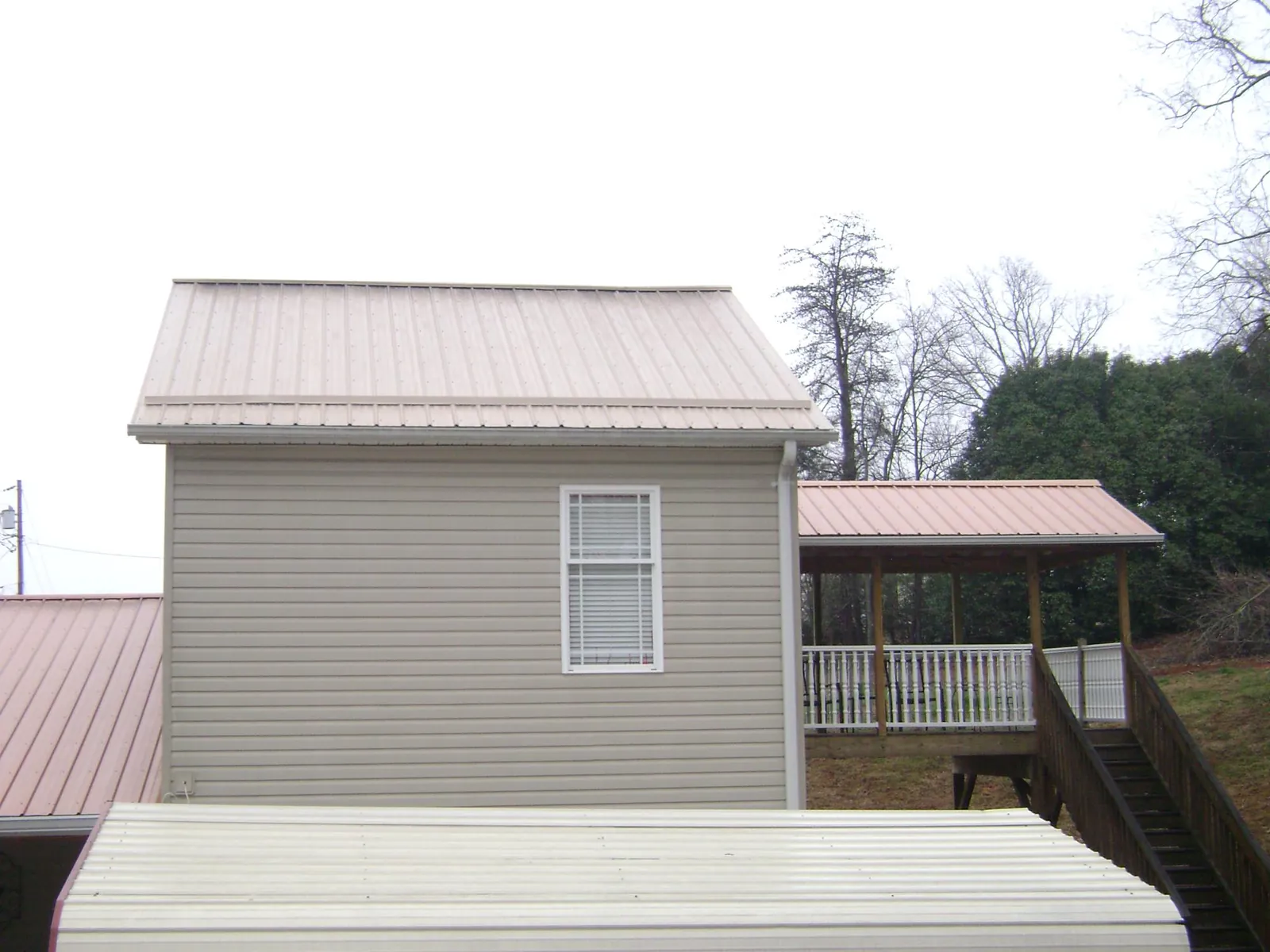 Tan metal roofs on a two story addition and attached porch, from a Roof Replacement job in Penn Run