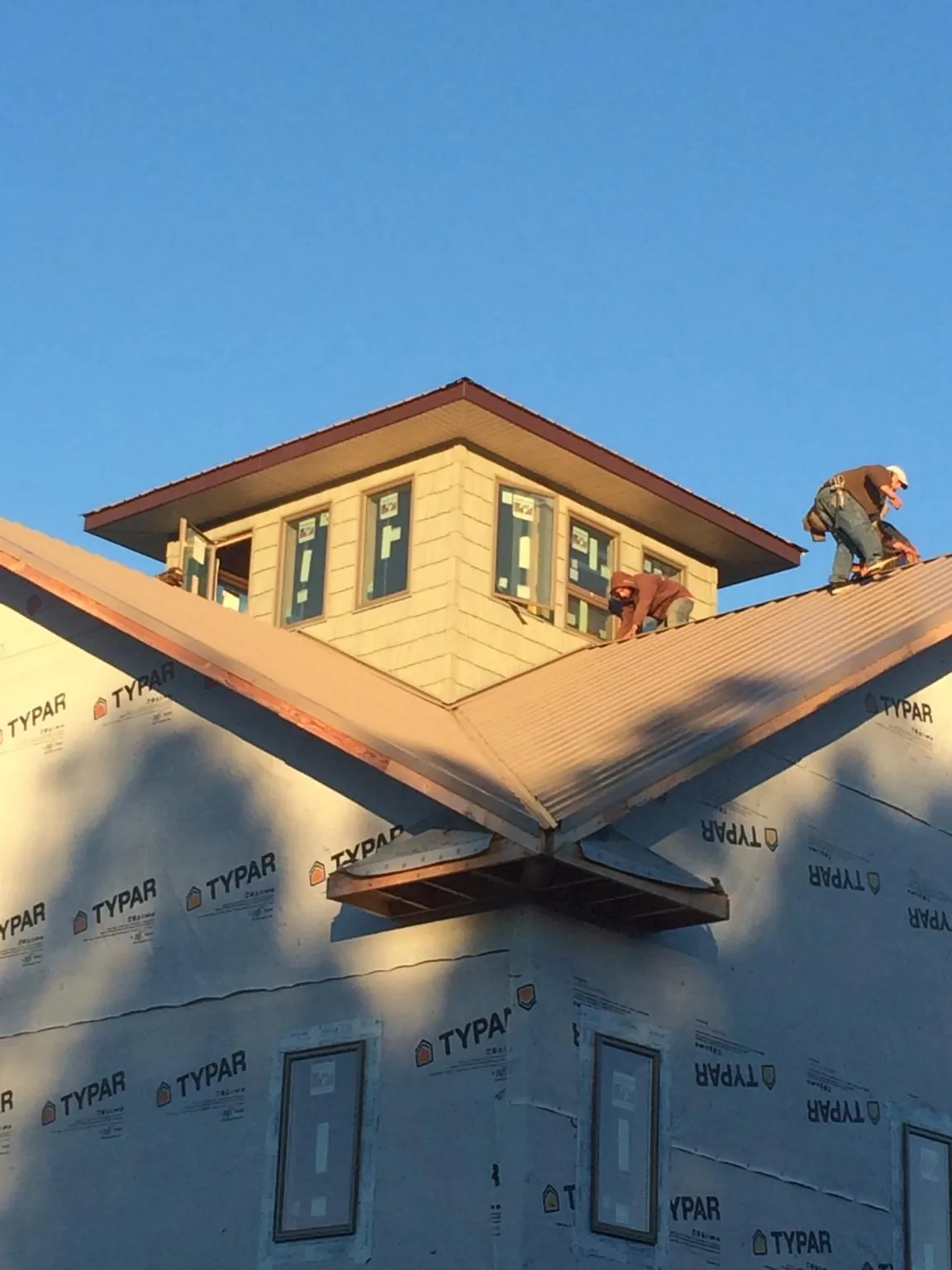 Roofers working around a rooftop cupola on a new metal roof at sunset — Roof Waterproofing in Penn Run by Roofing Brothers